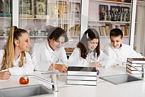 Chemistry lesson in labaratory in school. Pupils writing homework, smiling and having fun together in school laboratory.