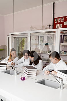 Chemistry lesson in labaratory in school. Pupils writing homework, smiling and having fun together in school laboratory.