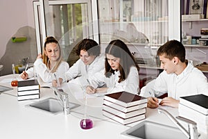 Chemistry lesson in labaratory in school. Pupils writing homework, smiling and having fun together in school laboratory.