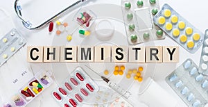 CHEMISTRY medicine word on wooden blocks on a desk. Medical concept with pills, vitamins, stethoscope and syringe on the