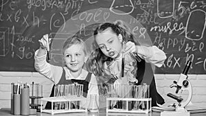 At chemistry school. School children performing experiment in science classroom. Schoolgirls holding test tubes. Science