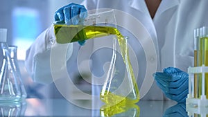 Chemistry scientist pouring yellow oily substance in test tube, petrol quality