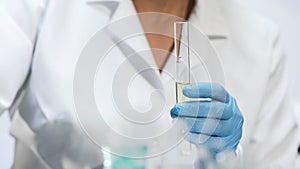 Chemistry student holding test tube with yellow liquid, doing medical research