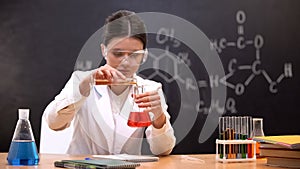 Chemistry student mixing liquids in scientific laboratory, conducting experiment