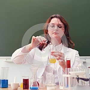 The chemistry teacher pours the reagent from the bottle into the test tubes. Scientific tests and research in the school