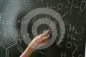 chemistry teacher writing and explane chemical formula on class board
