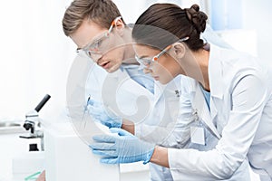 Chemists in protective glasses and gloves making experiment in lab