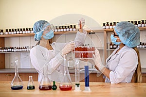 Chemists working in laboratory. Young women in protective uniforms with test tubes making experiments
