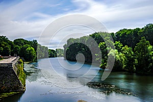 Cher river with smooth reflection under blue sky running through green forest