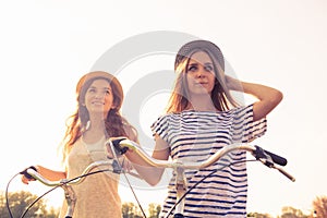 Cherful happy girls with hat ride bicycles on the park photo