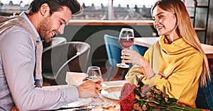 Cherful talking in restaurant. Couple holding red wine in glasses in restaurant photo