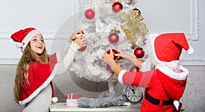 Cherished holiday activity. Kids in santa hats decorating christmas tree. Family tradition concept. Children decorating