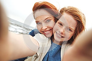 Cherishing every moment together. a mother and her young daughter taking a selfie at the waterfront.