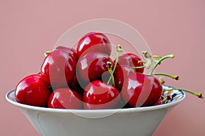 Cherries in a bowl wiyh pink background