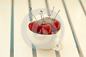 Cherries Chile in Heart-shaped mug on wood .