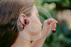 Cherries on the ears of a girl, close-up