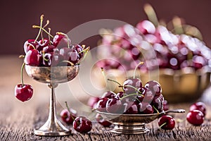 Cherries. Fresh sweet cherries. Delicious cherries with water drops in retro bowl on old oak table