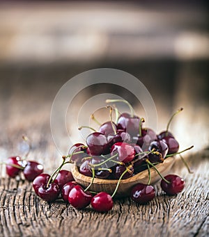 Cherries. Fresh sweet cherries. Delicious cherries with water drops in retro bowl on old oak table