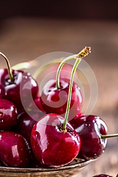 Cherries. Fresh sweet cherries. Delicious cherries with water drops in retro bowl on old oak table