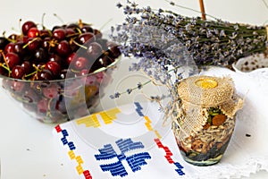 Cherries in glass bowl, honey with nuts in jar and lavender flowers