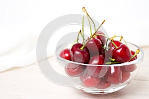 Cherries in glass dish. Cherry on wood and white background. - healthy eating and food concept