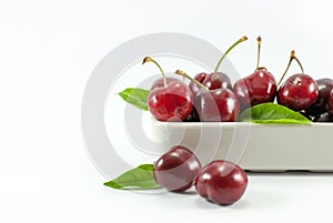 Cherries are housed in white ceramic vessels on a white floor.