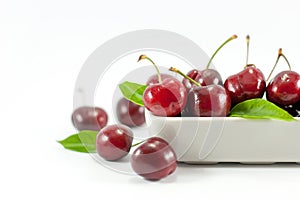 Cherries are housed in white ceramic on a white background.