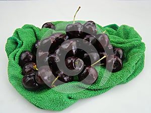 Fresh cherries fruits wrapped in cloth on green background