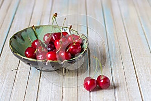 Cherries in a plate on a wooden table. Fresh red cherry