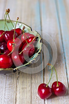 Cherries in a plate on a wooden table. Fresh red cherry