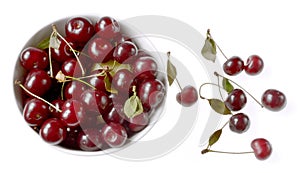 Cherries are poured into a cup, next to several cherries berries, isolated on white background