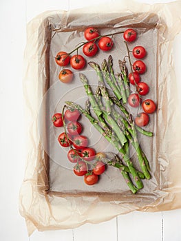cherries tomatoes and asparragus on a baking parchment