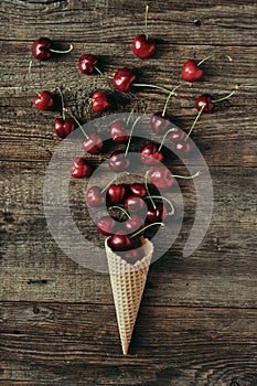 Cherries in waffle cone on wooden table, healthy snack, concept flat lay photography and content for food blog