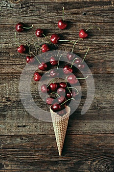 Cherries in waffle cone on wooden table, healthy snack, concept flat lay photography and content for food blog