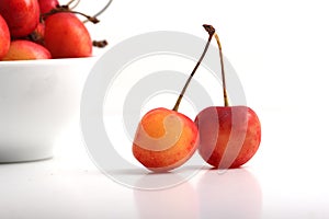 Cherries on white background with a bowl on the background