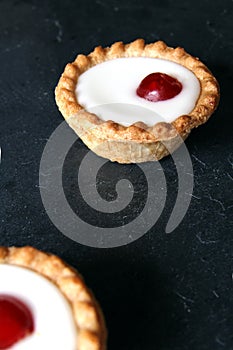 Cherry bakewell tarts on dark background