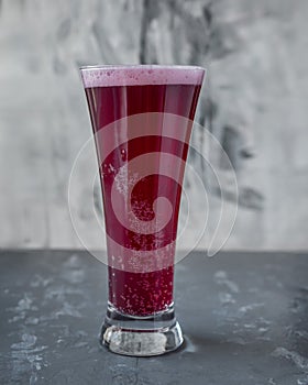 Cherry beer in tall glass goblet on gray background