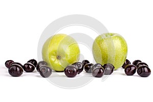 Cherry berries and two big green apples on white background isolated close up macro