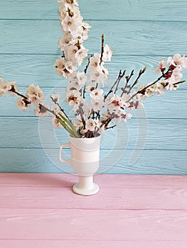 Cherry blossom branch leaves vintage beautiful in a vase on a colored wooden background, spring,