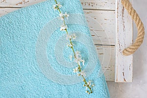 cherry blossom branch and turquoise towel on a white wooden background.