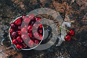 Cherry in bowl top view wooden background