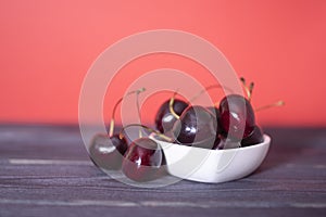 Cherry in a ceramic saucer on a black and red background