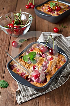 Cherry clafouti in portional ceramic forms on rustic wooden background