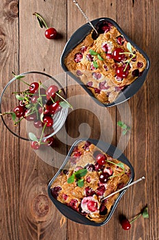 Cherry clafouti in portional ceramic forms on rustic wooden background