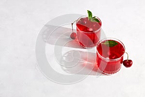 Cherry cocktail with ice on a light grey background. Top view, copy space