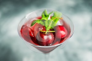 Cherry cocktail in martini glass with berries and mint leaves