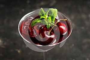 Cherry cocktail in martini glass with berries and mint leaves