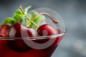 Cherry cocktail in martini glass with berries and mint leaves