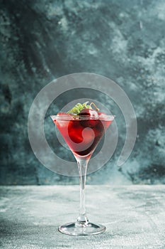 Cherry cocktail in martini glass with berries and mint leaves