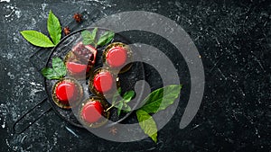 Cherry cream-mousse dessert with cherries and mint on a black stone plate. Top view. Rustic style